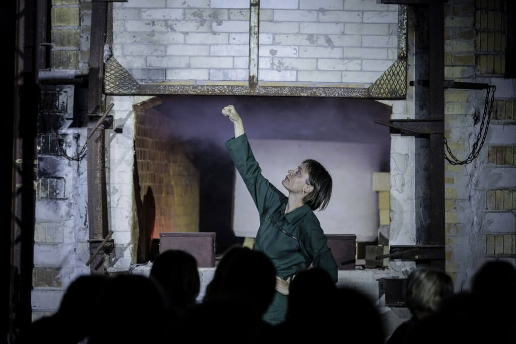 Eine Frau im Profil. Sie streckt ihr Faust in die Höhe.