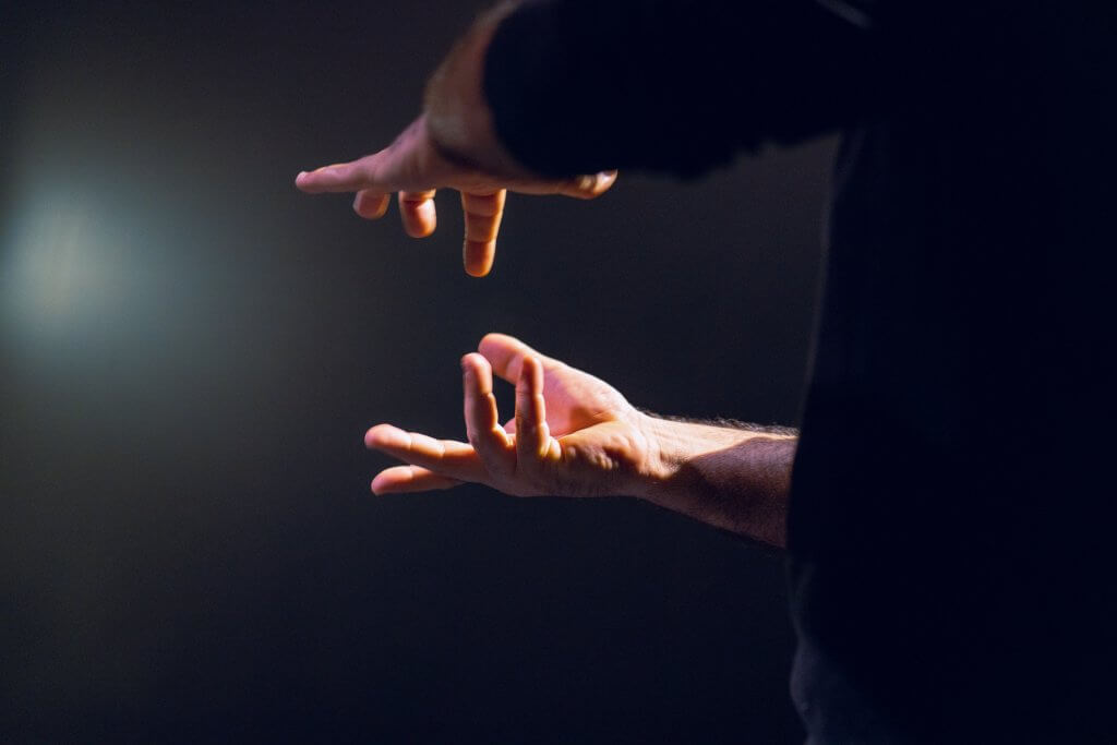 Zwei Hände mit abgespreizten Fingern in werden angestrahlt.