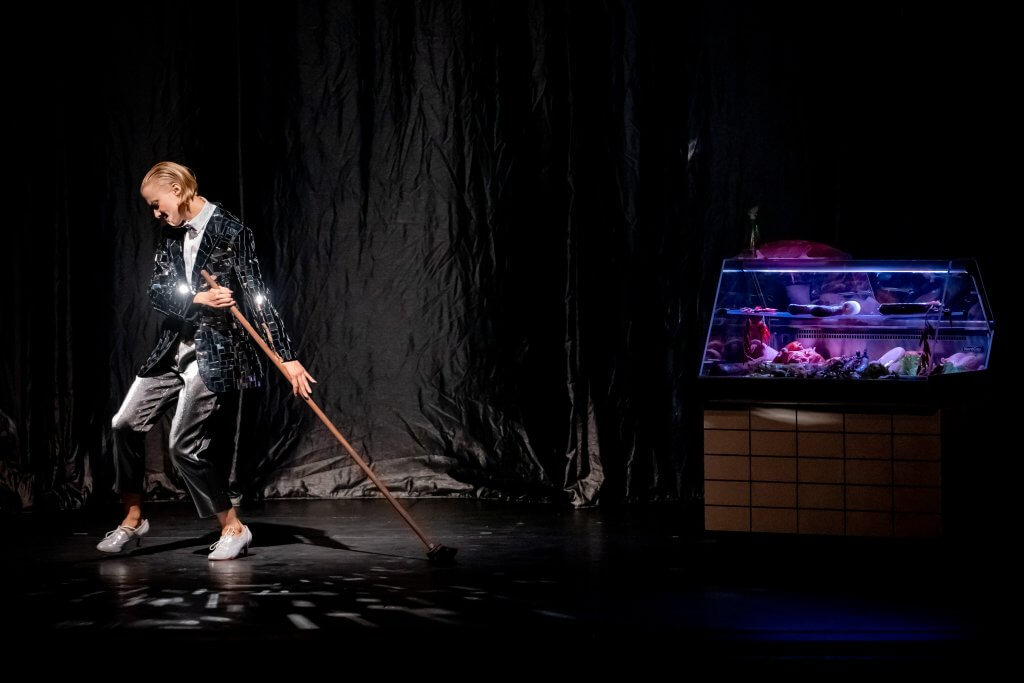 Eine Frau wischt tänzelnd über eine Bühne.