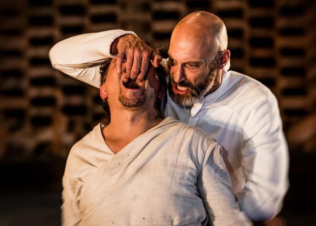 Ein Mann zieht den Kopf eines anderen brutal nach hinten.