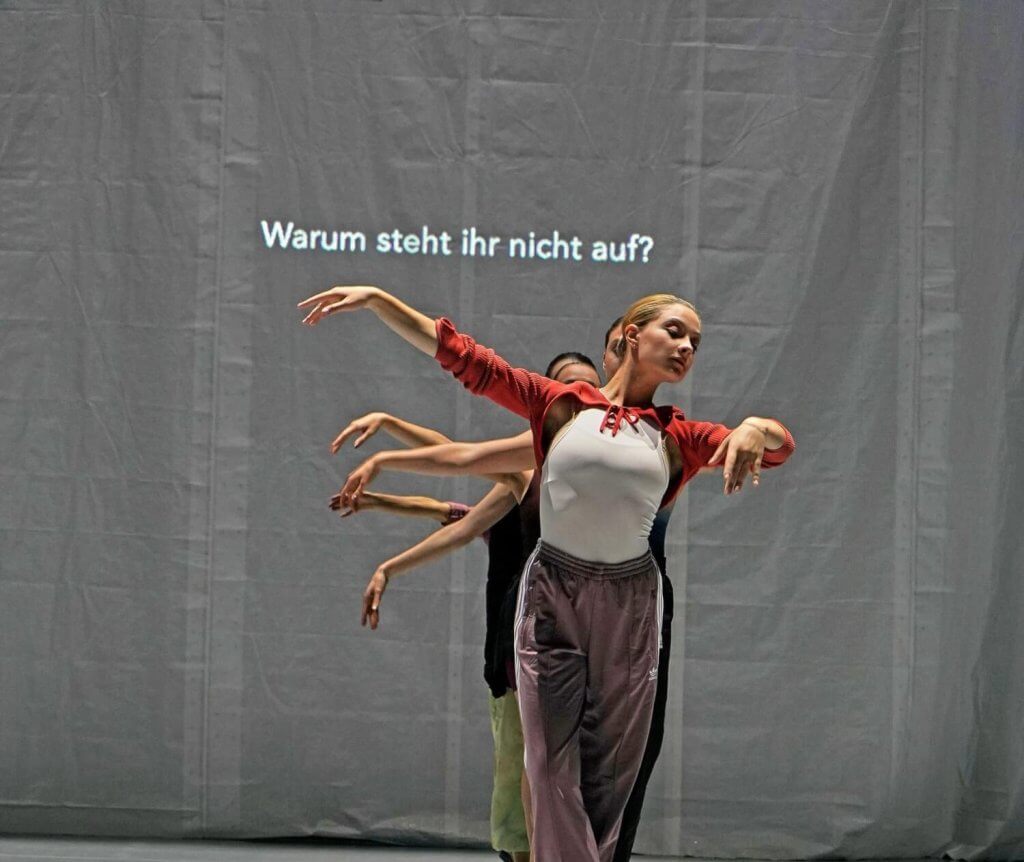 Tänzerinnen stehen in einer Reihe hintereinander und strecken ihre rechten Arme zur Seite.