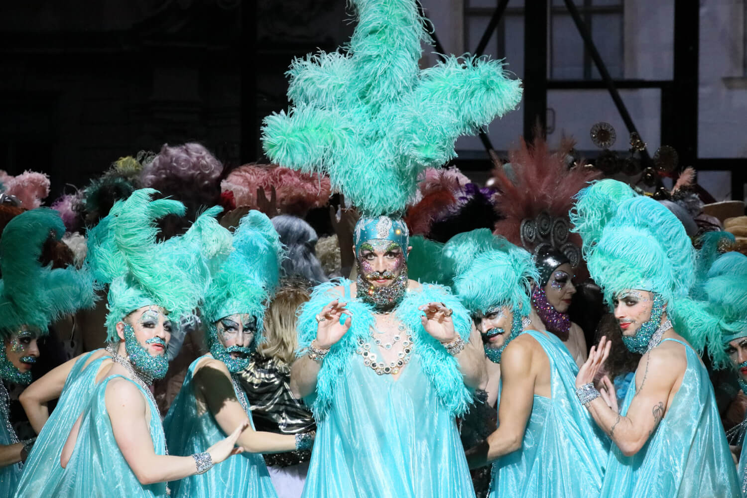 Darstellende mit türkisen Kostümen und Federn auf dem Kopf