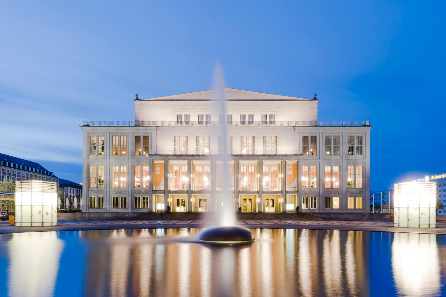 Zu sehen ist die Oper Leipzig. Im Vordergrund der Augustusplatz mit Wasserfontäne.