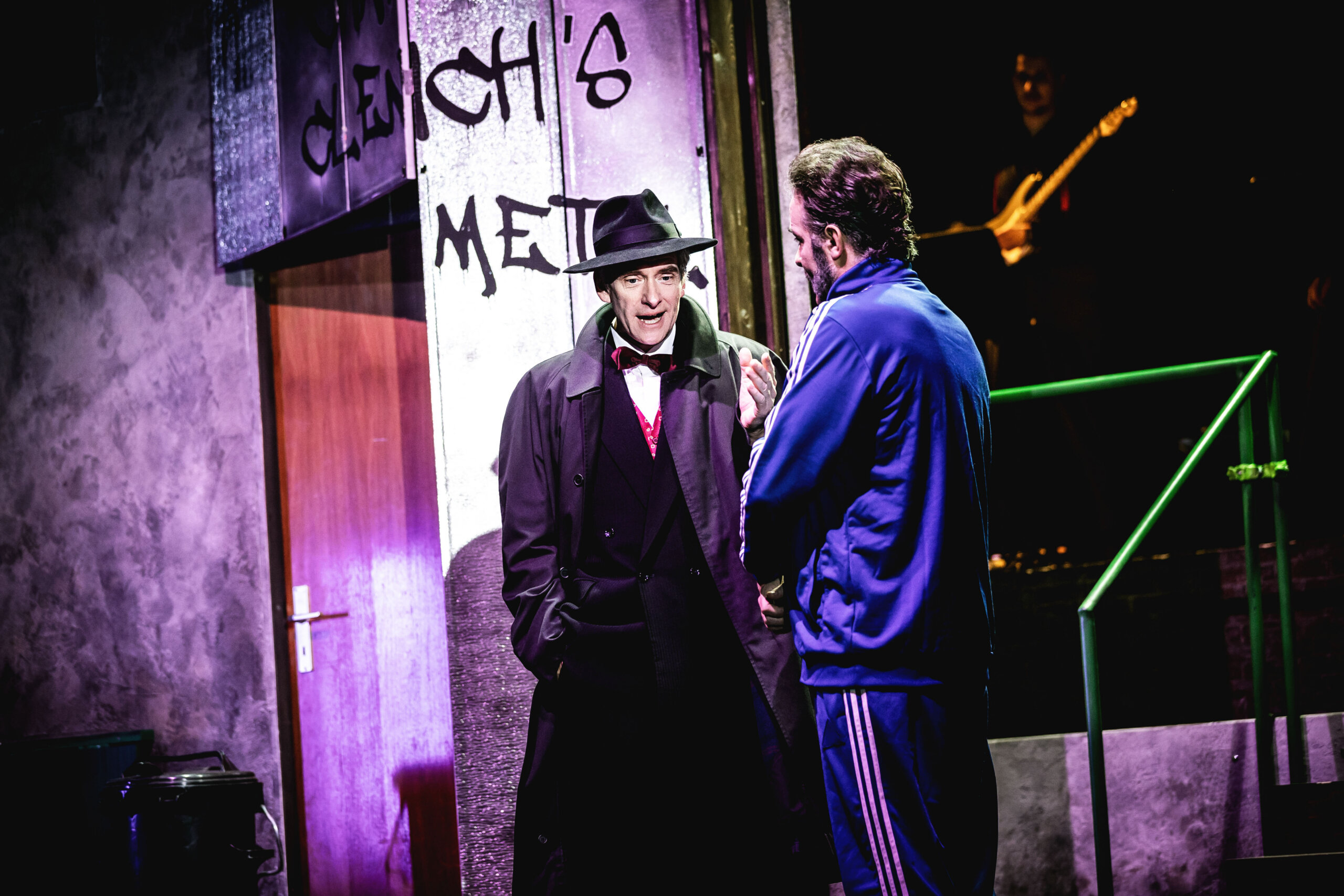 Thomas Wenzel und Dirk Boether stehen sich gegenüber. Der eine in Anzug, Fliege und edlem Mantel, der andere im violetten Jogginganzug.