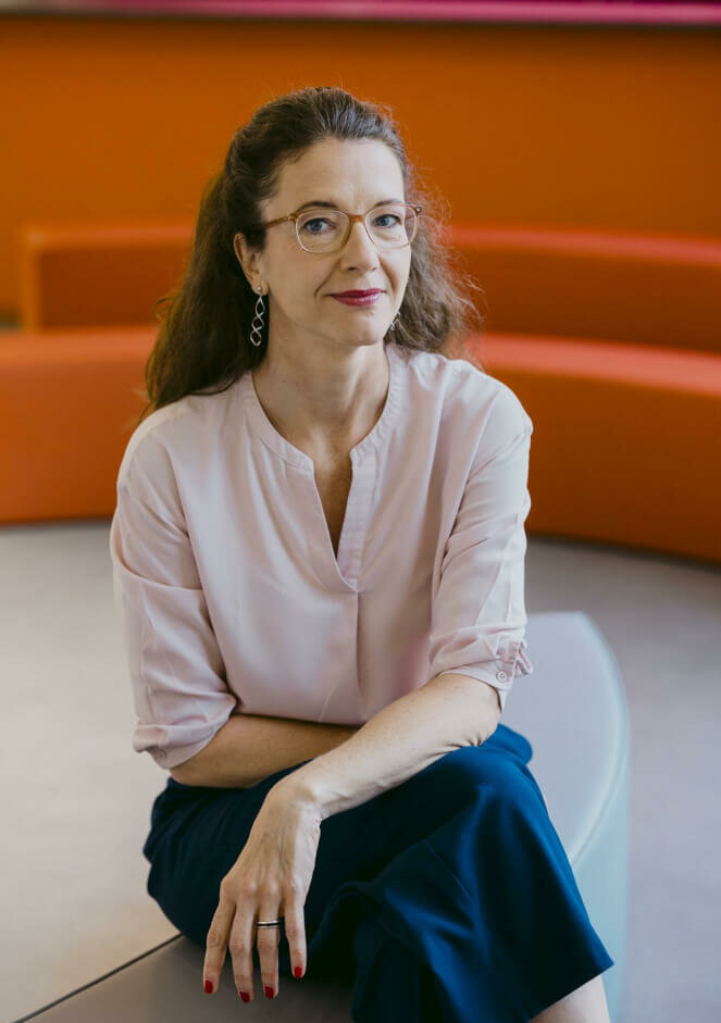 Zu sehen ist Christina Schulz, Intendantin des Theater an der Parkaue, sitzend mit übereinandergeschlagenen Beinen.