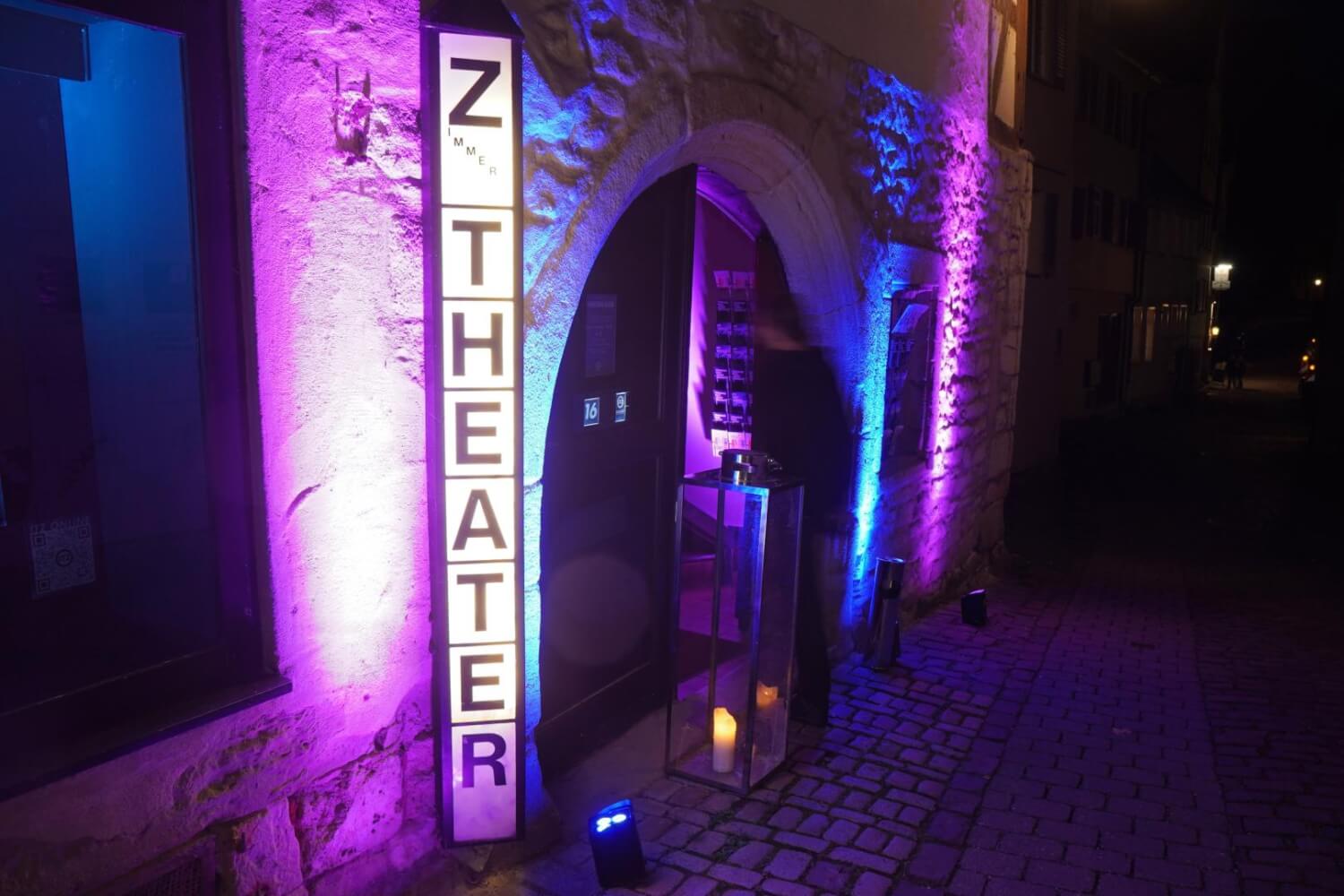 Man sieht das Zimmertheater Tübingen, beleuchtet in lila und blau.