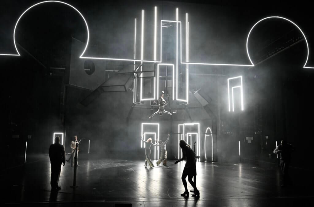 schwarze Silhouetten vor dem dunklen Bühnenbild mit kubischen und runden Leuchtrahmen von „Solaris“ am Schauspiel Frankfurt