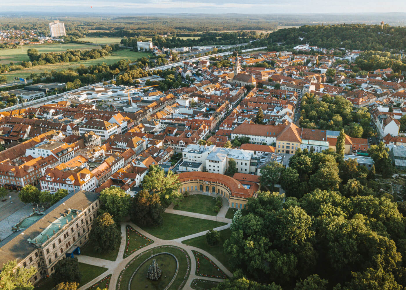 Erlangen von oben. Aufgenommen mit einer Drohne, sieht man unten den Schlossgarten mit Orangerie, dahinter liegt das Markgrafentheater, rechts Bäume, weiter hinten ragt eine Kirche raus und der Burgberg, links hinten der Lange Johann.