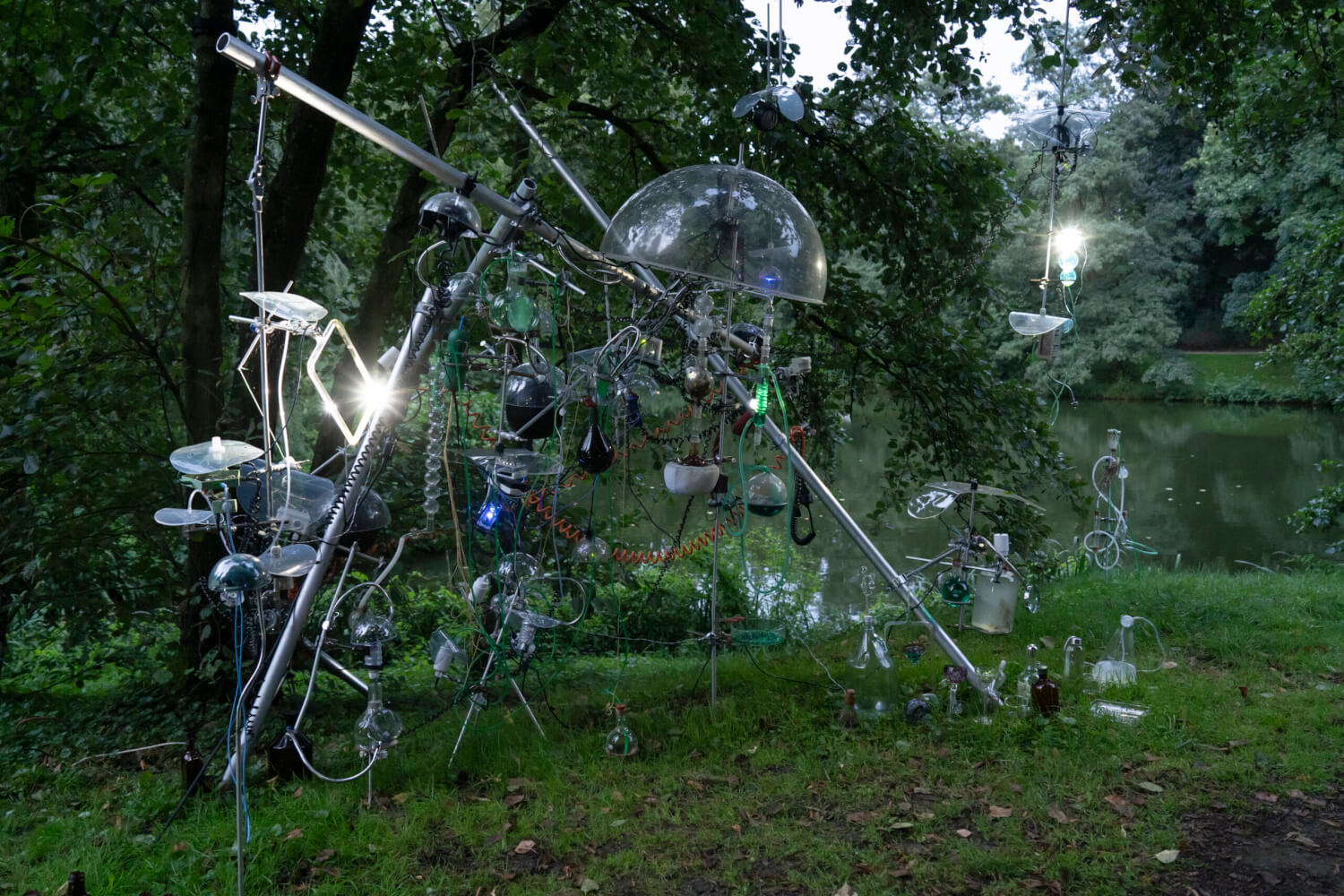 Man sieht den RAUSCHgeneration, eine Installation der RaumZeitPiraten im Kunstparcours, der vor einem Gewässer und mitten im Grünen steht.