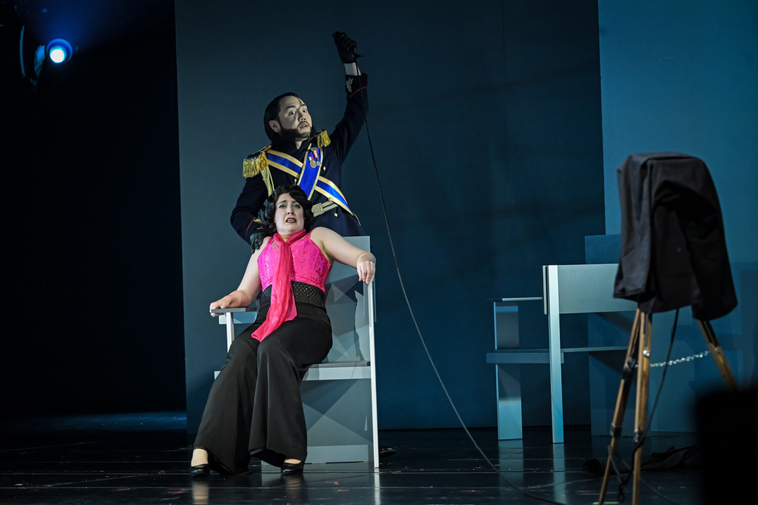 Zinzi Frohwein sitzt als falsche Angèle auf dem Porträtstuhl in einem Fotoatelier. Der Zar (Hyunkyum Kim) steht hinter ihr und betätigt den Auslöser der Kamera über eine Schnur.