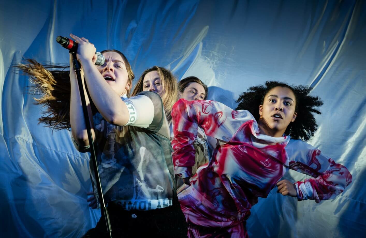 Vier Darsteller:innen schauen direkt und fordernd in die Kamera