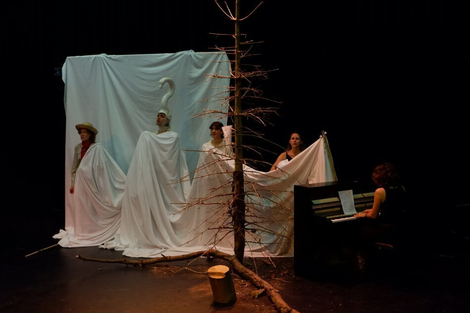 Darstellende vor einem weißen Tuch, dahinter ein weißes Tuch im Hintergrund