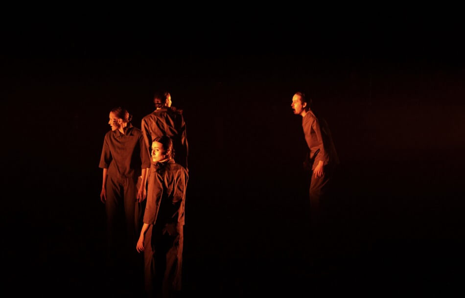 vier Darstellende auf einer dunklen Bühne, suchend