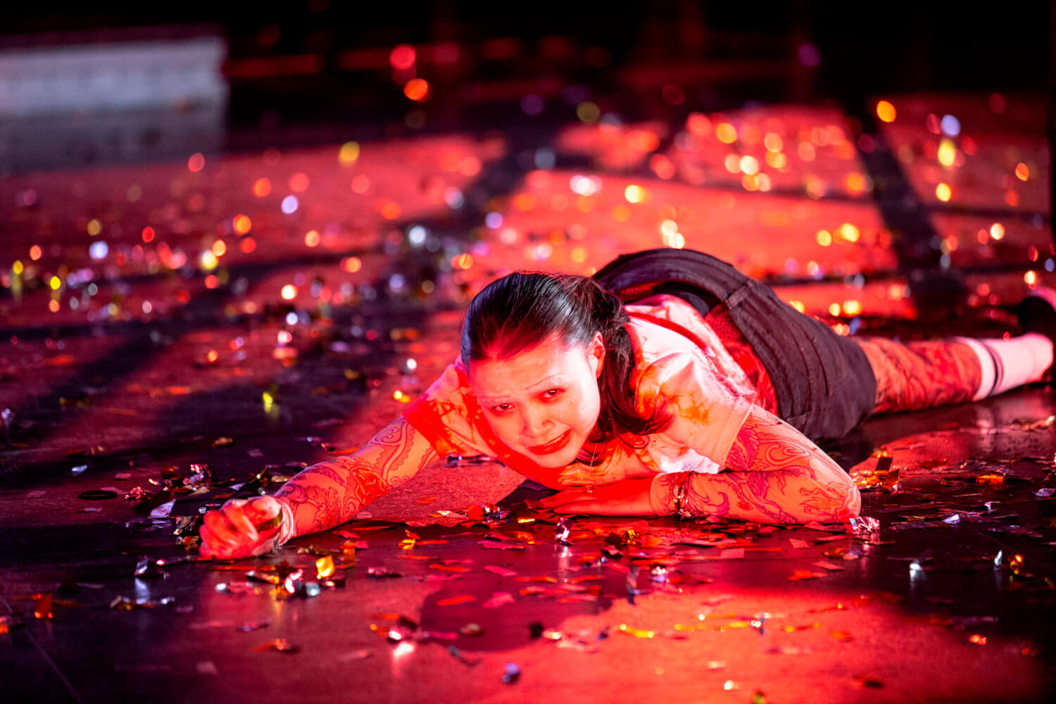 Sari Bluhm liegt auf dem Boden und schaut schmerzverzerrt in die Kamera.