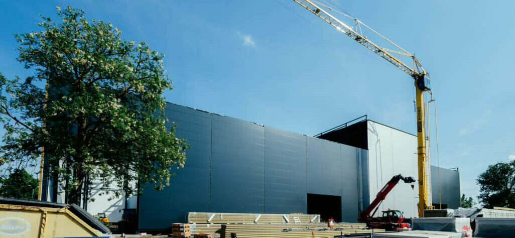 Ein Gebäude, eine Leichtbauhalle, vor dem ein Kran steht