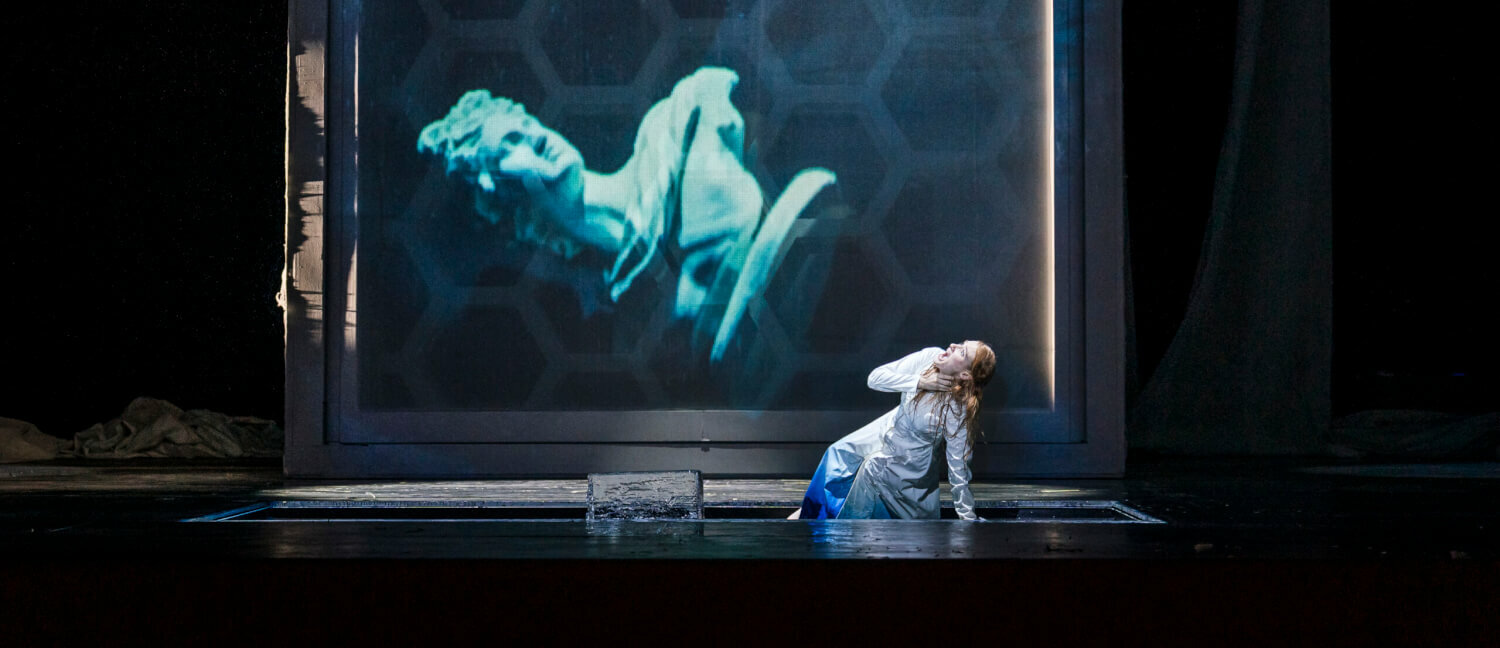 Auf einer Leinwand wird eine Büste angezeigt. Davor hockt Jessica Niles (Sandra) und sieht erschrocken zur Büste auf.