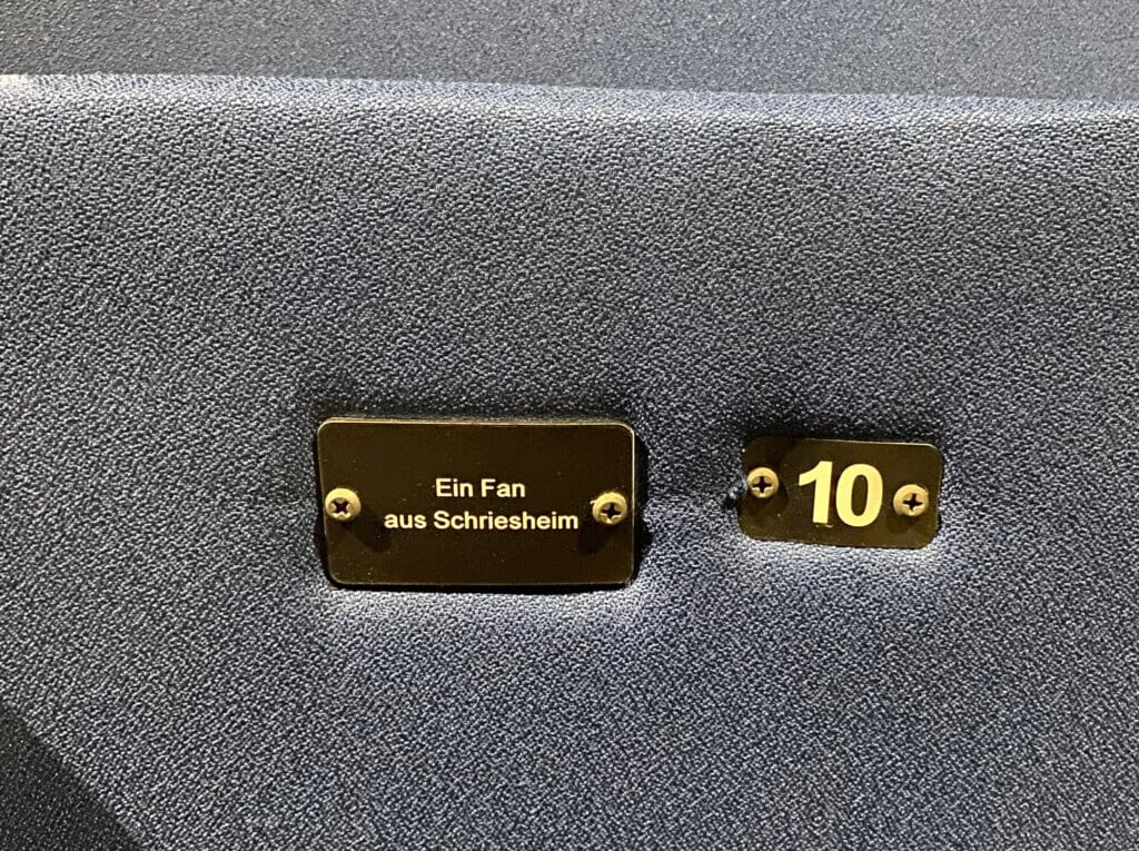 Eine goldene Plakette an einem Klappsitz mit der Sitznummer 10 daneben