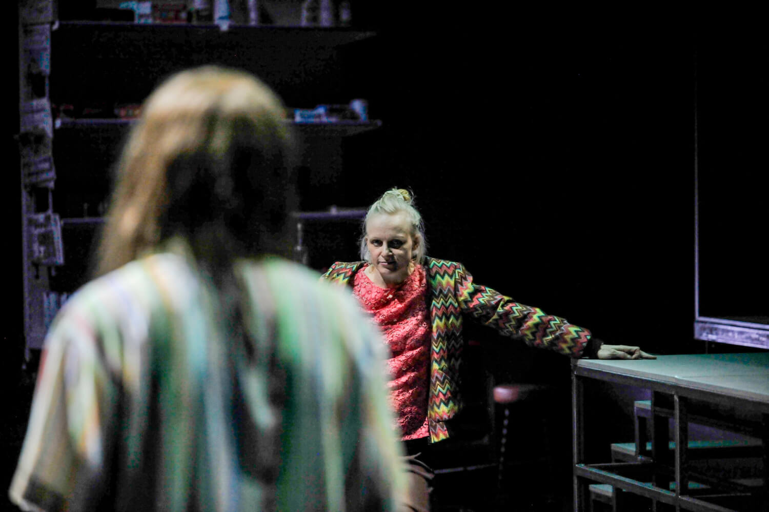 Im Vordergrund steht eine Person mit dem Rücken zur Kamera. Sie schaut auf eine Person im Hintergrund, die sie herausfordernd anstarrt.