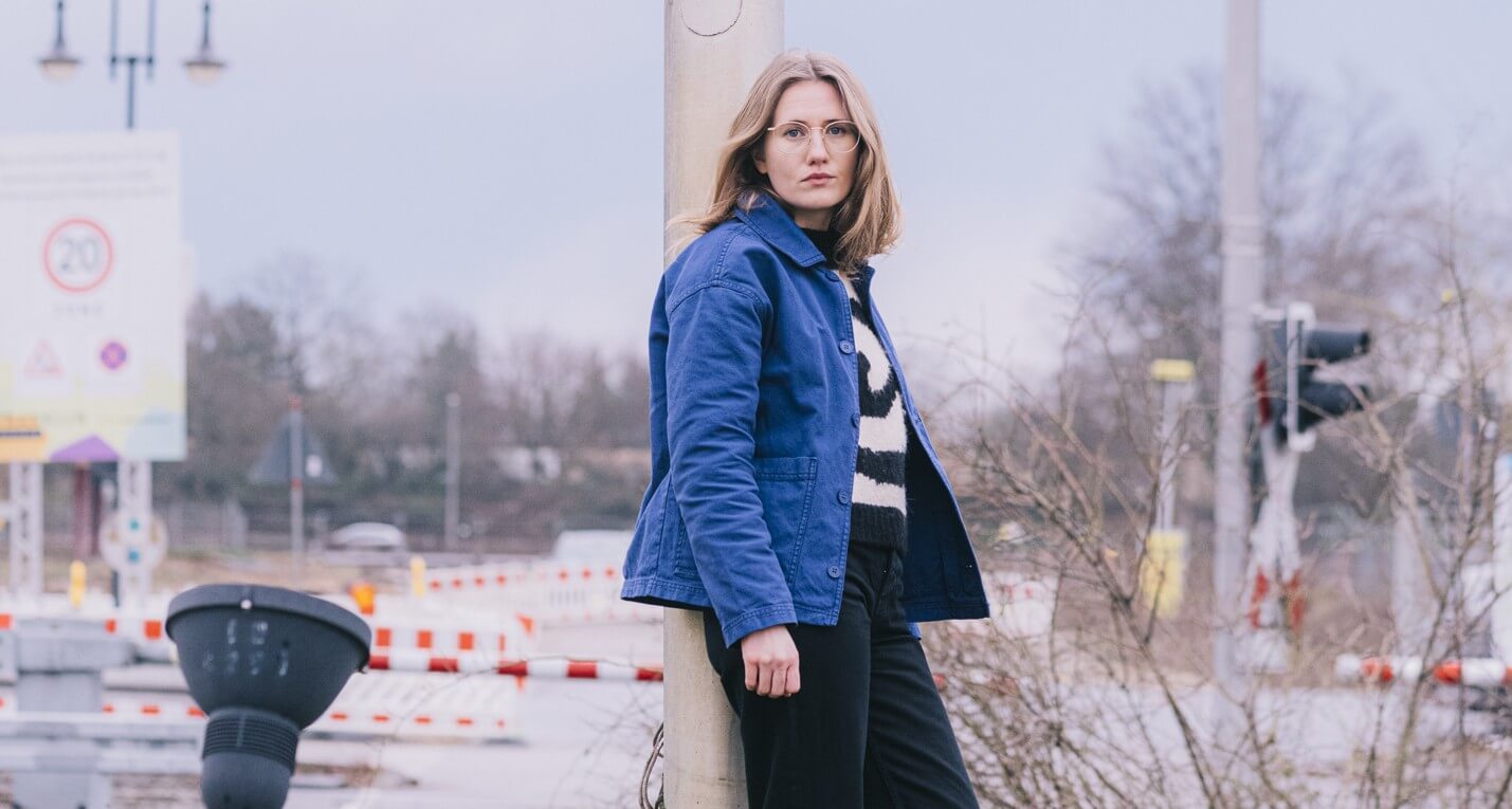 Zu sehen ist die Geschäftsführende Dramaturgin am Nationaltheater Mannheim, Lena Wontorra. Sie lehnt an einer Straßenlaterne.