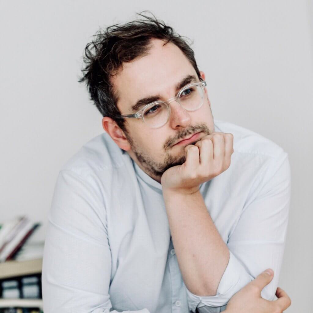 Zu sehen ist der Chefdramaturg des Landestheater Eisenach / Junges Schauspiel, Christoph Macha. Sein Kinn stützt er auf seinen linken Handballen auf.