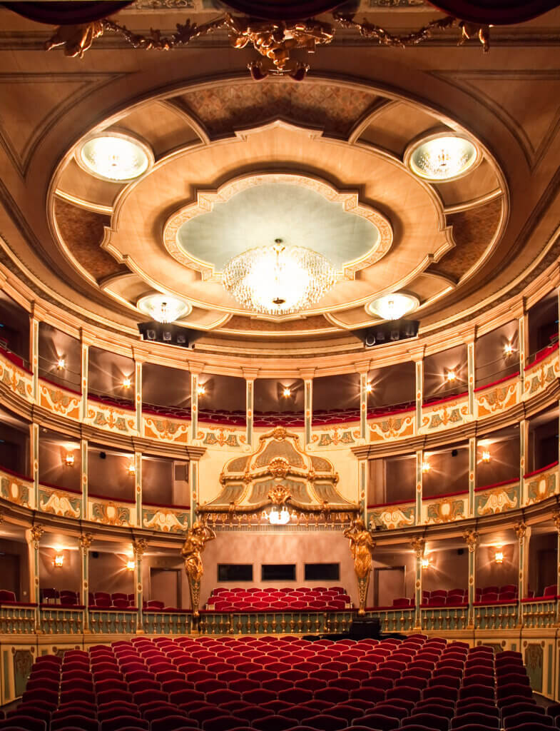 Markgrafentheater des schauspiel erlangen. Blick in den leeren Zuschauerraum in goldenem Licht. Roter Bestuhlung im Parkett, Hochparkett und zwei Rängen.