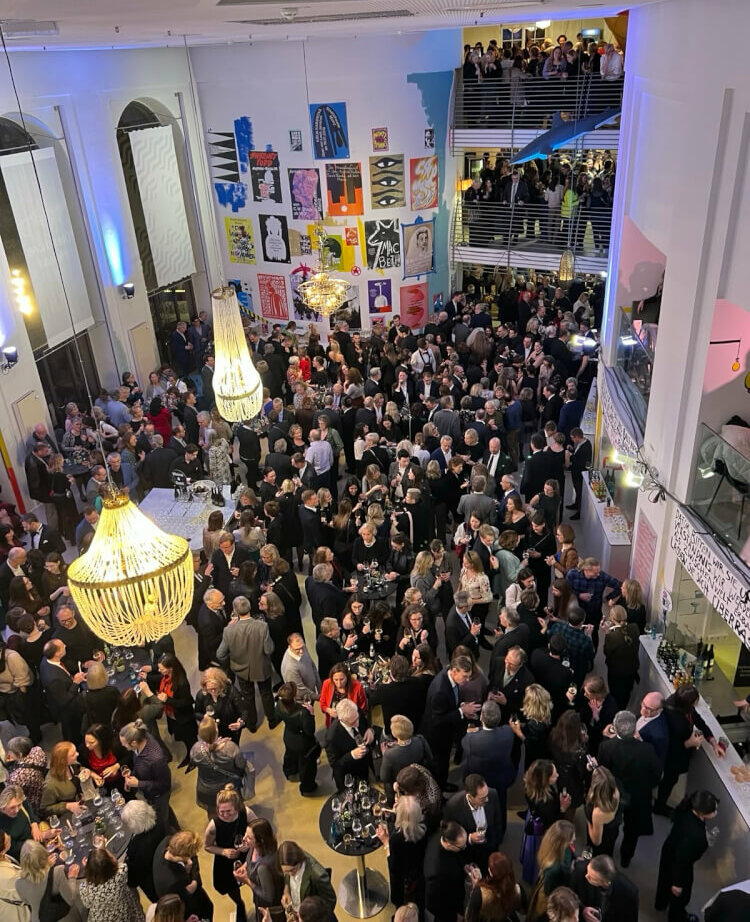 Das gefüllte Pausenfoyer des Staatstheater Mainz. Aus der Vogelperspektive sind Menschen zu sehen, die herumstehen und sich unterhalten.