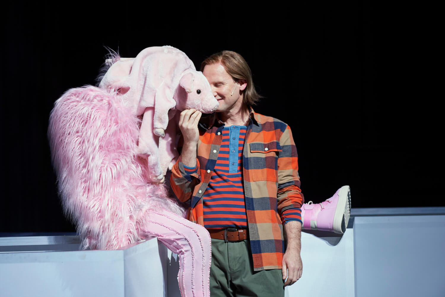 Aaron (Torben Kessler) steht neben seinem Plüschschwein (Cino Djavid) und hält seine Hand liebevoll an die Schnauze des Kuscheltiers.