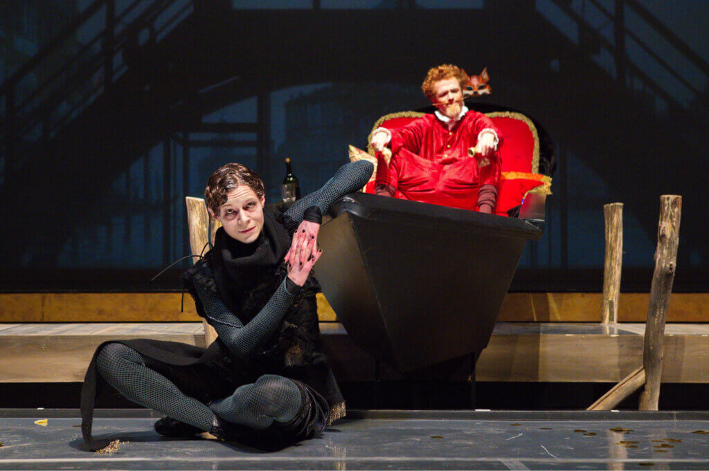 Volpone (Hagen Ritschel) sitzt in seiner Gondel. Katharina Paul sitzt als Schmeißfliege Mosca unterwürfig davor.