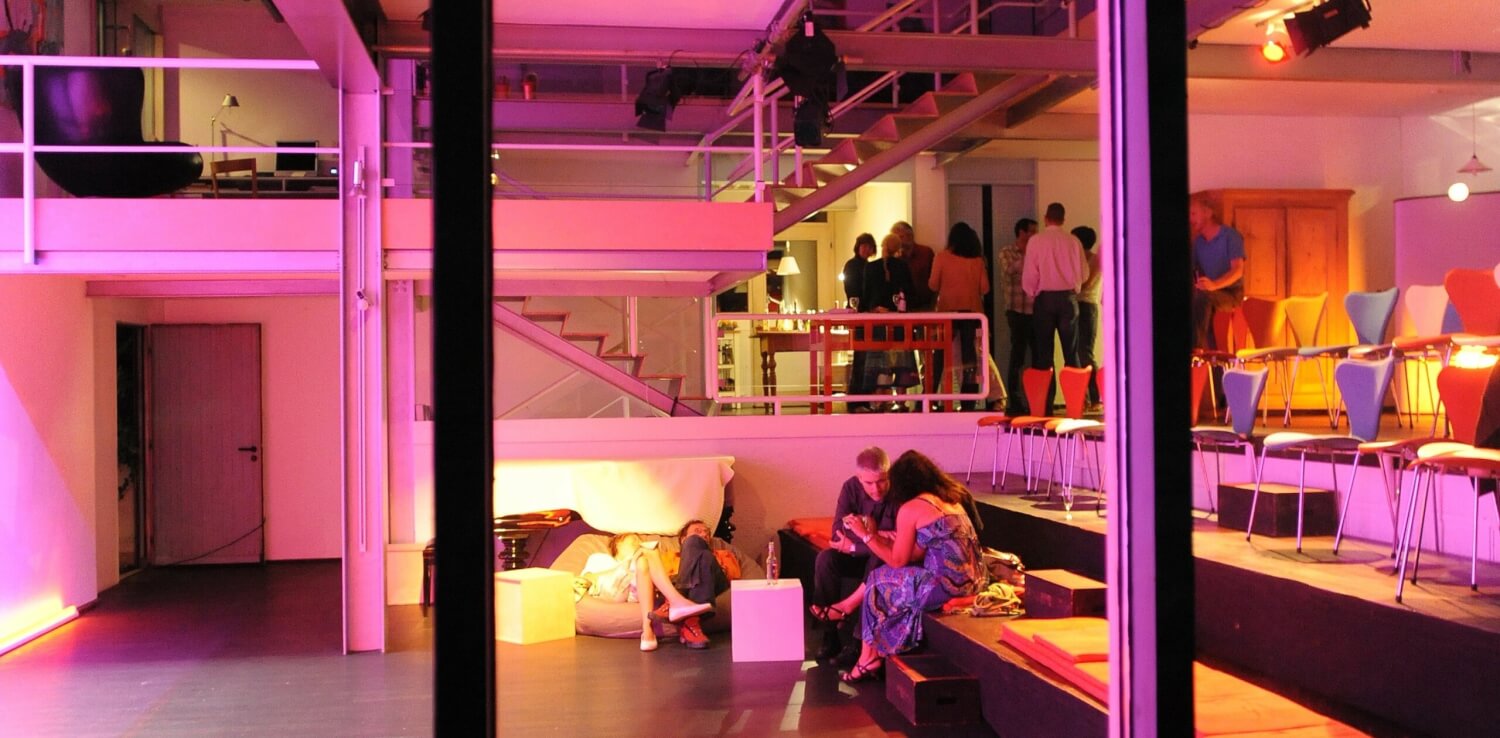 Eine Veranstaltung des Atelier Diagonale im Meta Theater. Zwei Pärchen sitzen auf der unteren Ebene. Auf der mittleren Ebene stehen zwei Stuhlreihen, dahinter stehen Menschen in Gruppen zusammen und unterhalten sich.