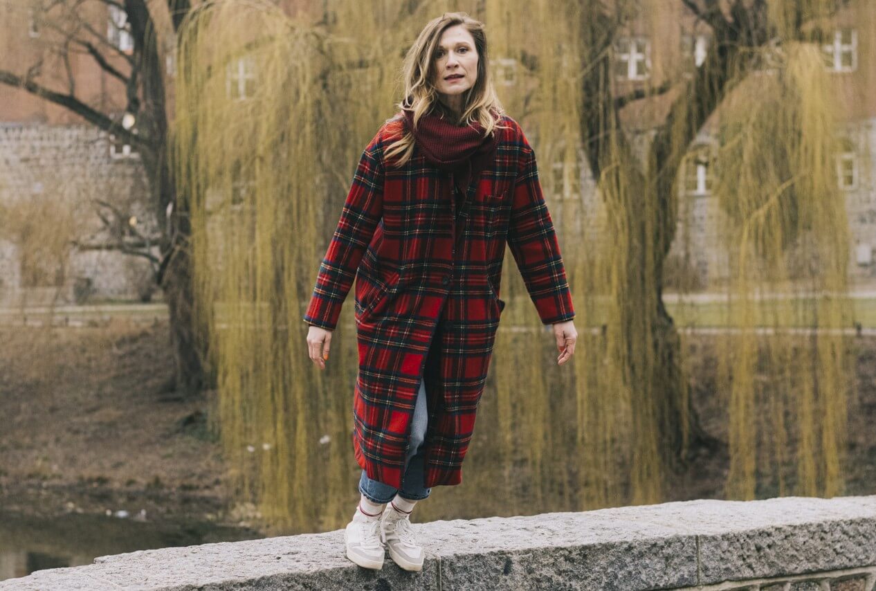 Julischka Eichel steht auf einer Steinmauer und lässt sich nach vorne fallen.